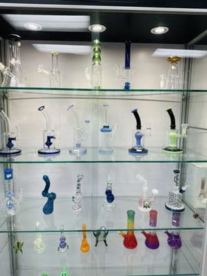 Glass display case with bongs, pipes, and rigs at Inhale Exhale Smoke